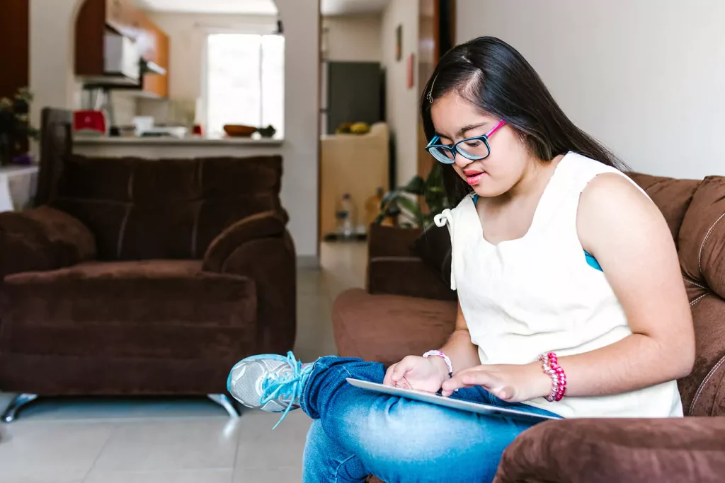 Disabled woman sitting on couch at home using iPad
