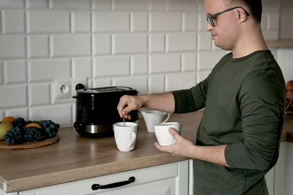 Disabled man with down syndrome making cup of coffee