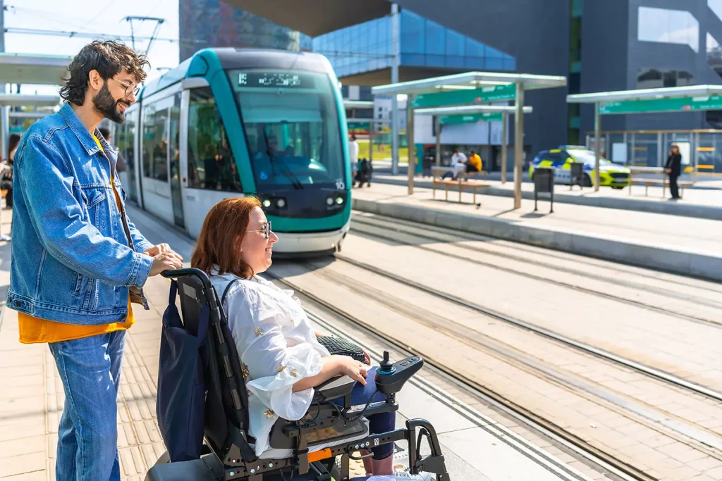 Support worker with disabled woman in wheelchair waiting to board train